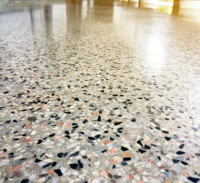 Polished terrazzo floor with multicolored stone chips and bright light reflections