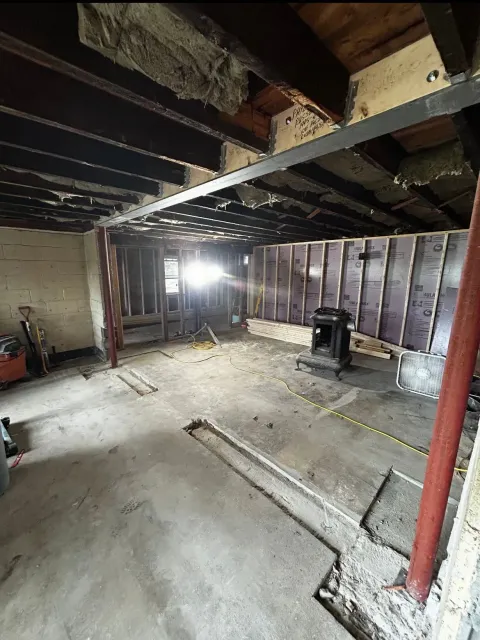 A large room with a lot of wooden beams and a concrete floor.