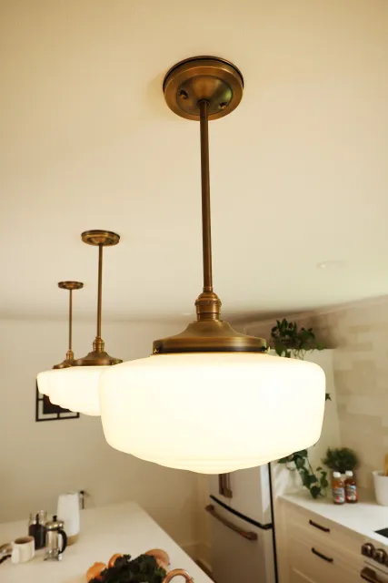 Three pendant lights with frosted glass shades hanging from the ceiling over a kitchen counter.