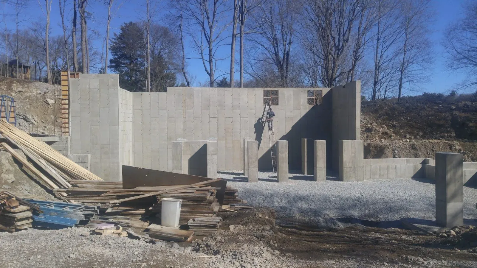 A concrete wall is being built in a field with trees in the background