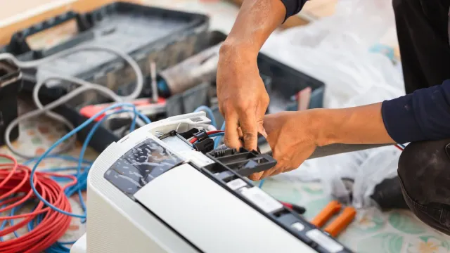 Technician model repairing indoor HVAC controls with wiring and service tools