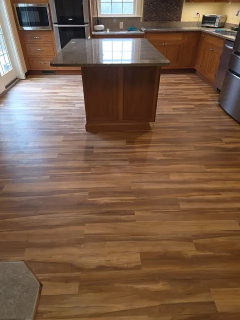Modern kitchen with wood cabinetry, center island with dark countertop, and hardwood flooring throughout