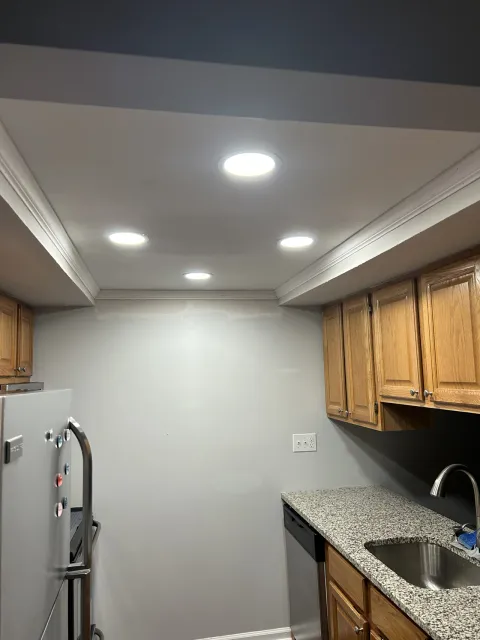 After ceiling work: recessed lights and crown molding above the same wood cabinets