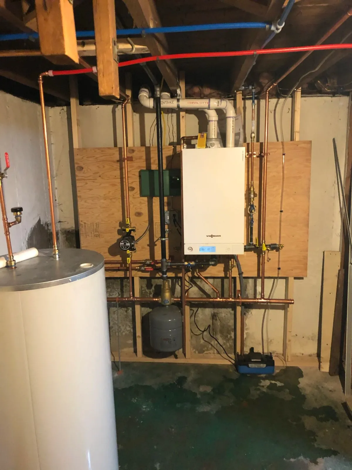 Basement area with hot water heater, boiler system, and pipes.