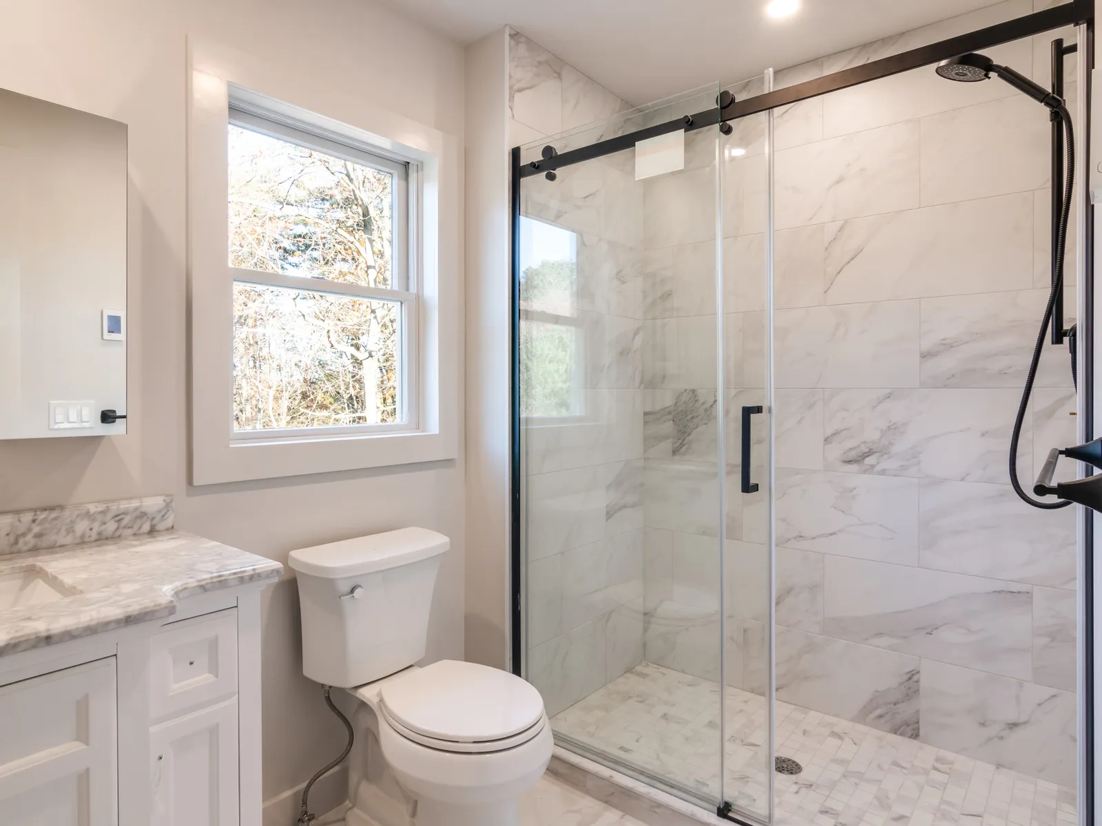 Remodeled bath with glass shower and marble tile
