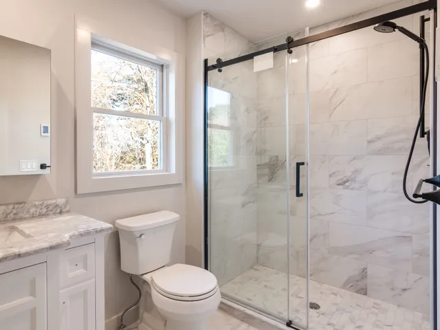 Remodeled bath with glass shower and marble tile