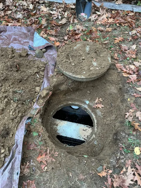Open access point with detached cover, surrounded by dirt and soil.