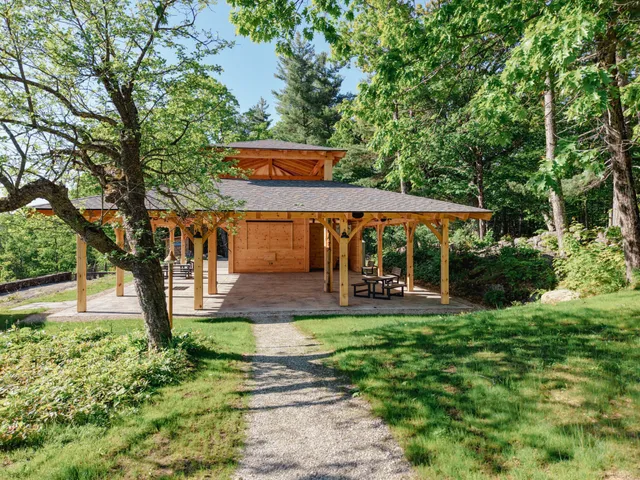 Accessible pathways lead to a wooden pavilion surrounded by lush greenery at the Harris Center for Conservation Education.