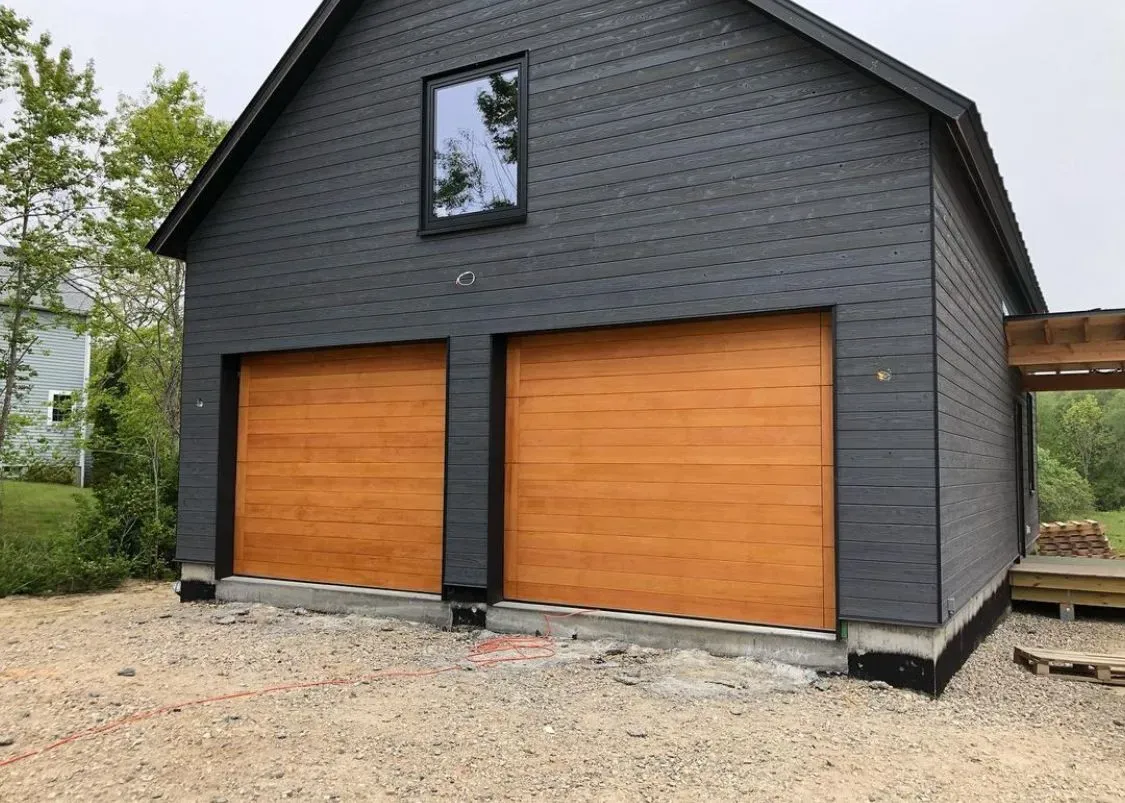 A black garage with two wooden garage doors and a window