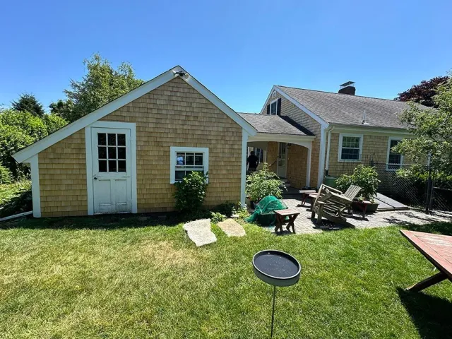A small house with a shed in the backyard.