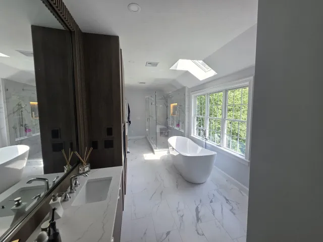 Completed bathroom after tile renovation with freestanding tub and glass shower