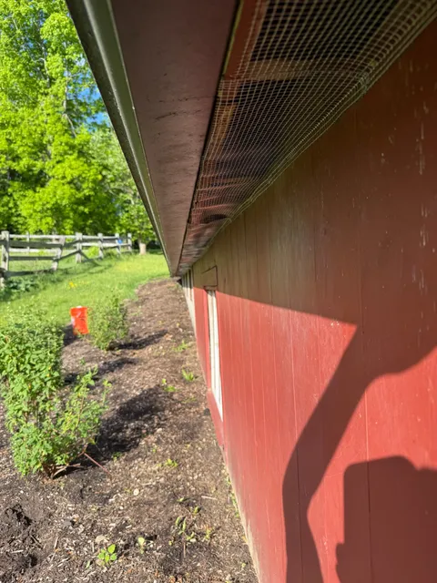 Hardware wire mesh installed under red barn eave line for pest exclusion
