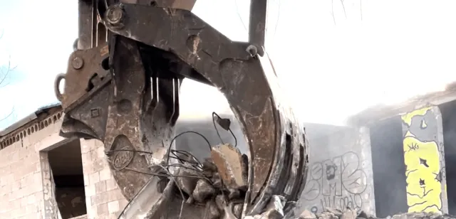 Sweeney, bucket claw holding debris, demolition-services-min