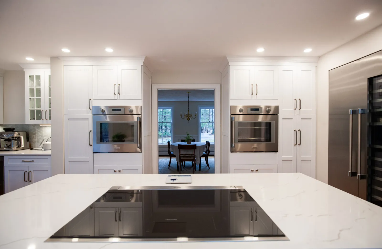 White kitchen with waterfall island and wall ovens