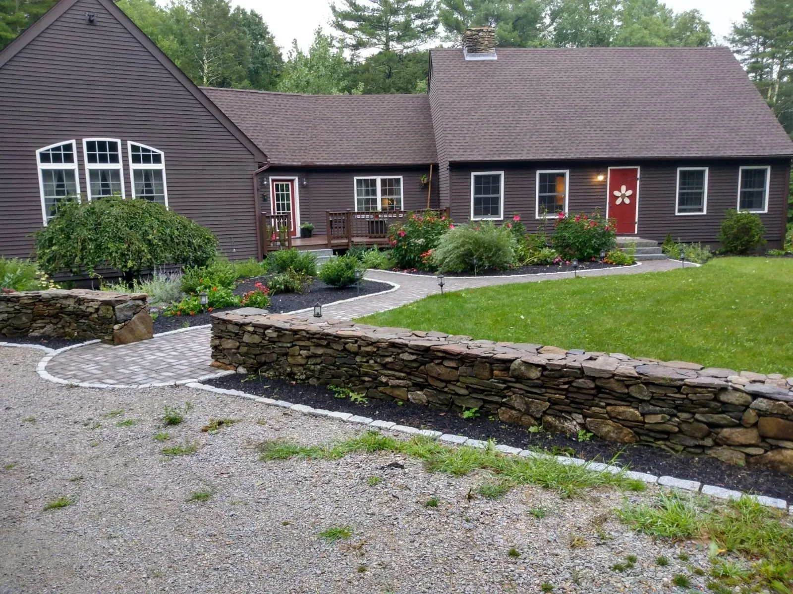 A brown house with a garden and stone pathway in a rural setting.