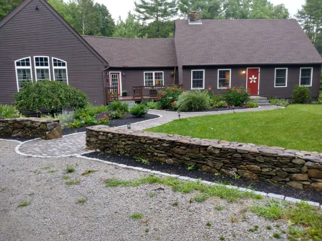 A brown house with a garden and stone pathway in a rural setting.