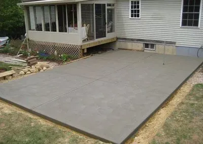 A concrete patio is being built in front of a house.