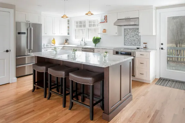 Modern kitchen with a dark brown island, white cabinets, and stainless steel appliances.