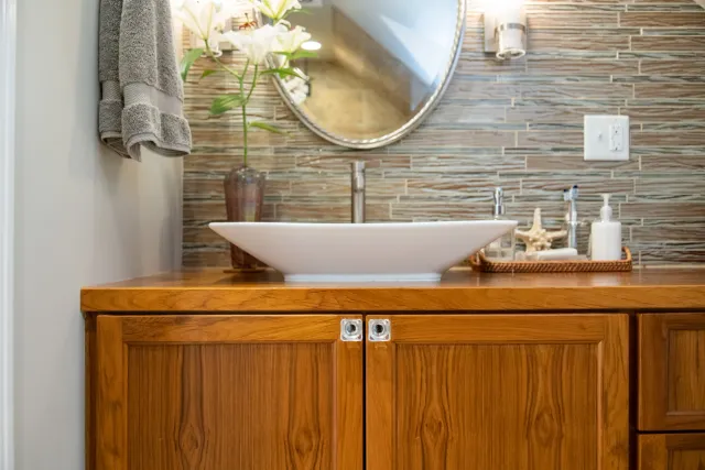 Jamaica Plain, MA — “Treetop attic” bathroom. A cramped bathroom in the eaves of an attic was expanded into this lush full bath that completes this treetop primary bedroom suite. The teak vanity was custom fabricated in our studio.