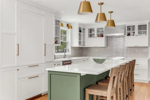 White Mouser kitchen with sage green island, brass pendants, and Calacatta Gold counters in Hingham, MA