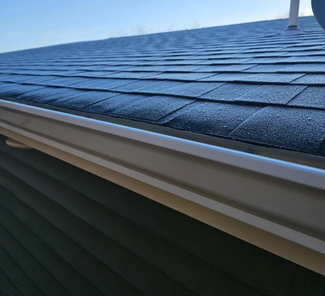 A black gutter is on the side of a white house.