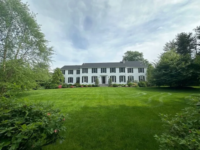 A large white house with a large lawn in front of it.