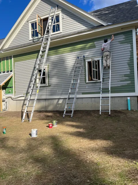 Paintable crew painting a Vermont home exterior from a ladder