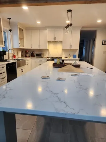 Full kitchen remodel in Seacoast NH featuring white shaker cabinets, large quartz island and modern tile flooring