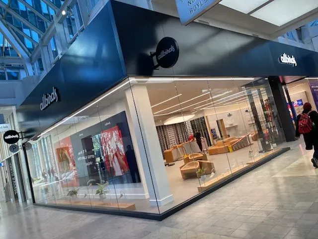 Mall storefront with glass windows, displaying furniture and a sign that reads