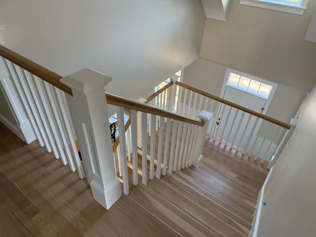 Custom staircase with white balusters and wood railings built by Miranda Finish Carpentry in New England