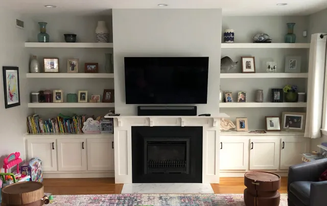 Custom mantle, cabinets, and floating shelves designed to fill two nooks in the client's home