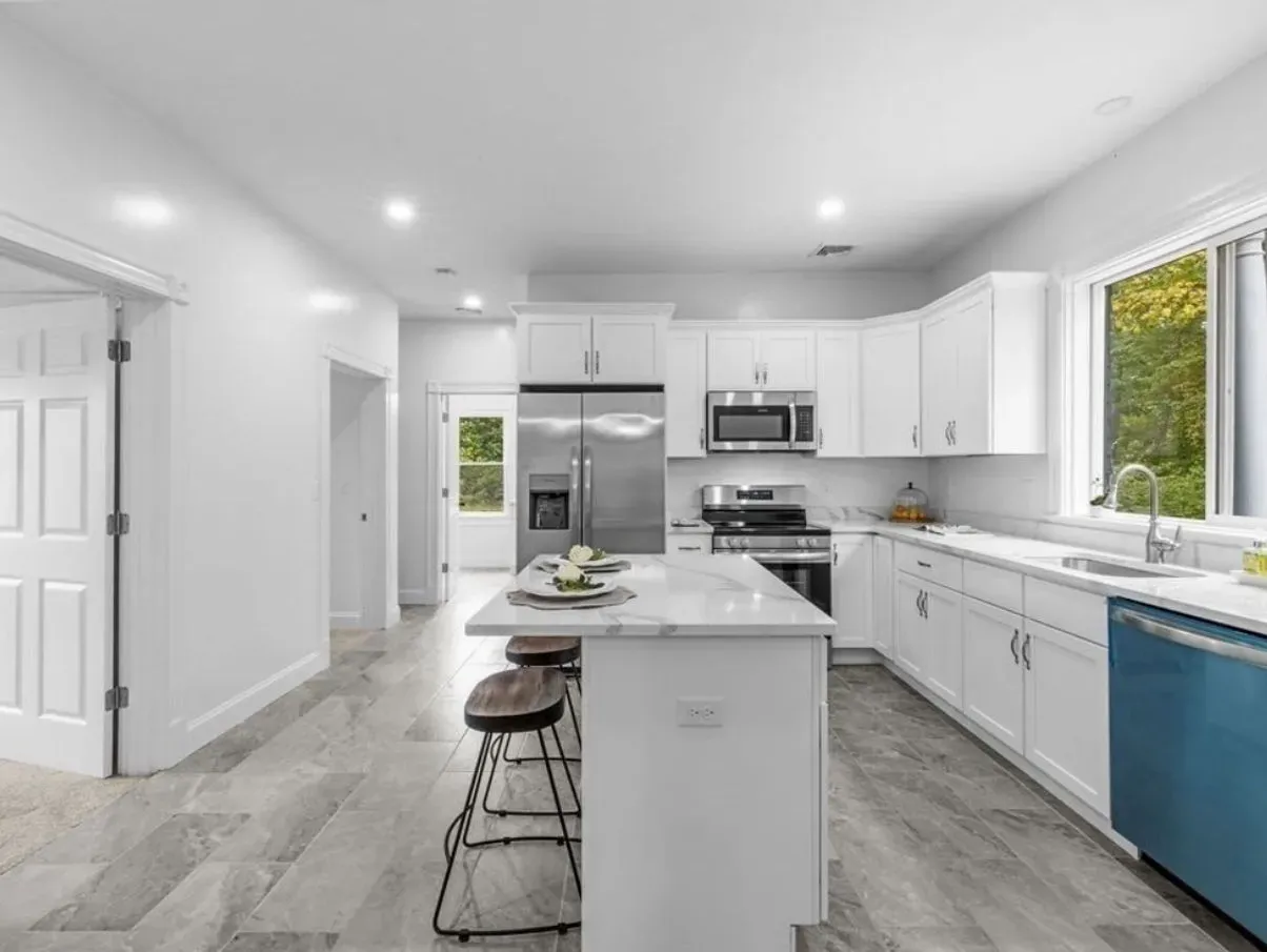 A kitchen with white cabinets , stainless steel appliances , and a blue dishwasher.