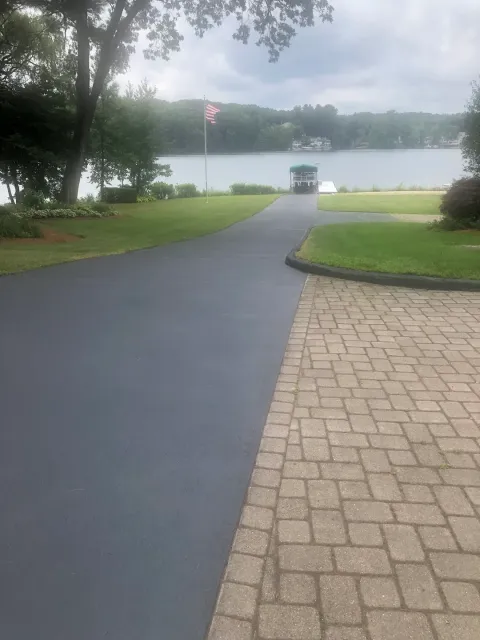 A paved road with trees and water in the background.