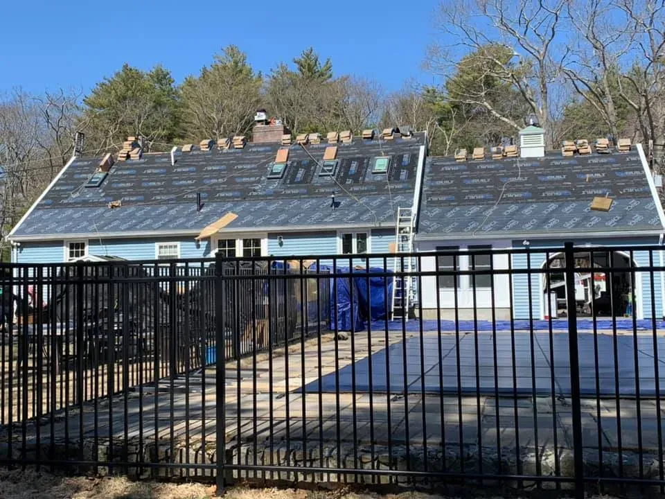 A fence surrounds a house that is being remodeled.