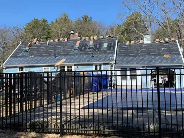 A fence surrounds a house that is being remodeled.