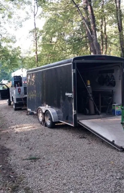 Mobile welding trailer setup in wooded area by Warrior Welding LLC, offering on-site welding services in NH, ME, and MA