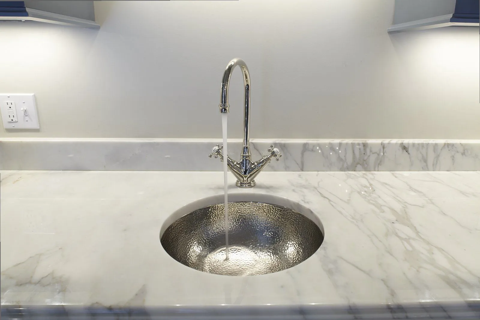 Hammered undermount basin with wall-mount faucet on marble