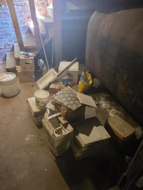 A basement corner cluttered beside the oil tank before the cleanout