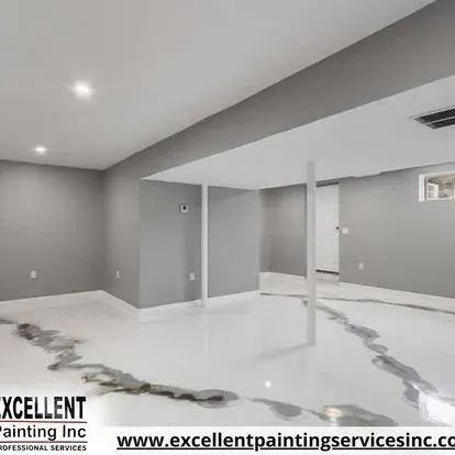 An empty basement with a white floor and gray walls.