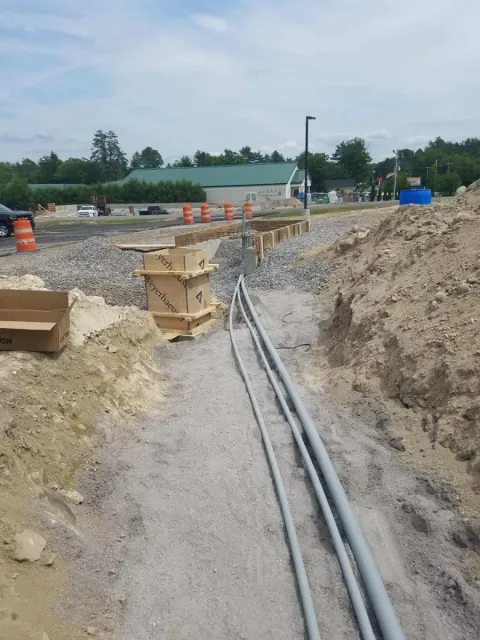 A bunch of pipes are laying in the dirt in a construction site.