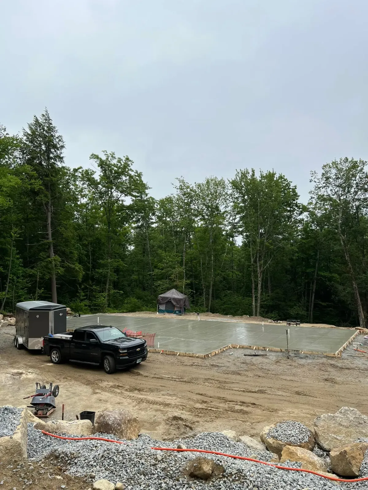 A truck is parked in a dirt lot next to a trailer.