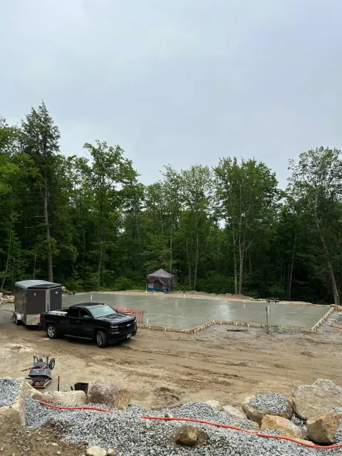 A truck is parked in a dirt lot next to a trailer.