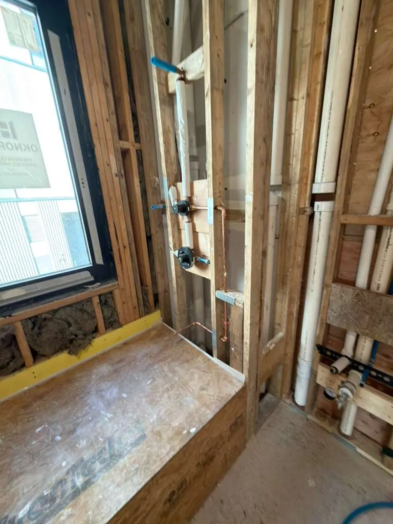 Bathroom rough plumbing installation with tub spout, handshower, and valve setup