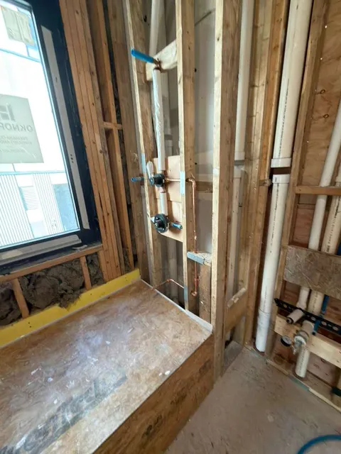 Bathroom rough plumbing installation with tub spout, handshower, and valve setup