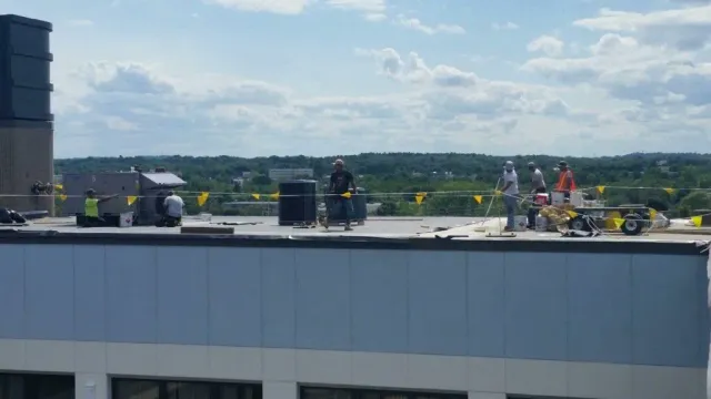 A group of construction workers are working on the roof of a building.
