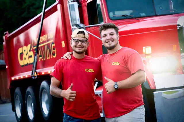 Two friendly masonry and paving experts giving a thumbs up in front of their service vehicle in Watertown.