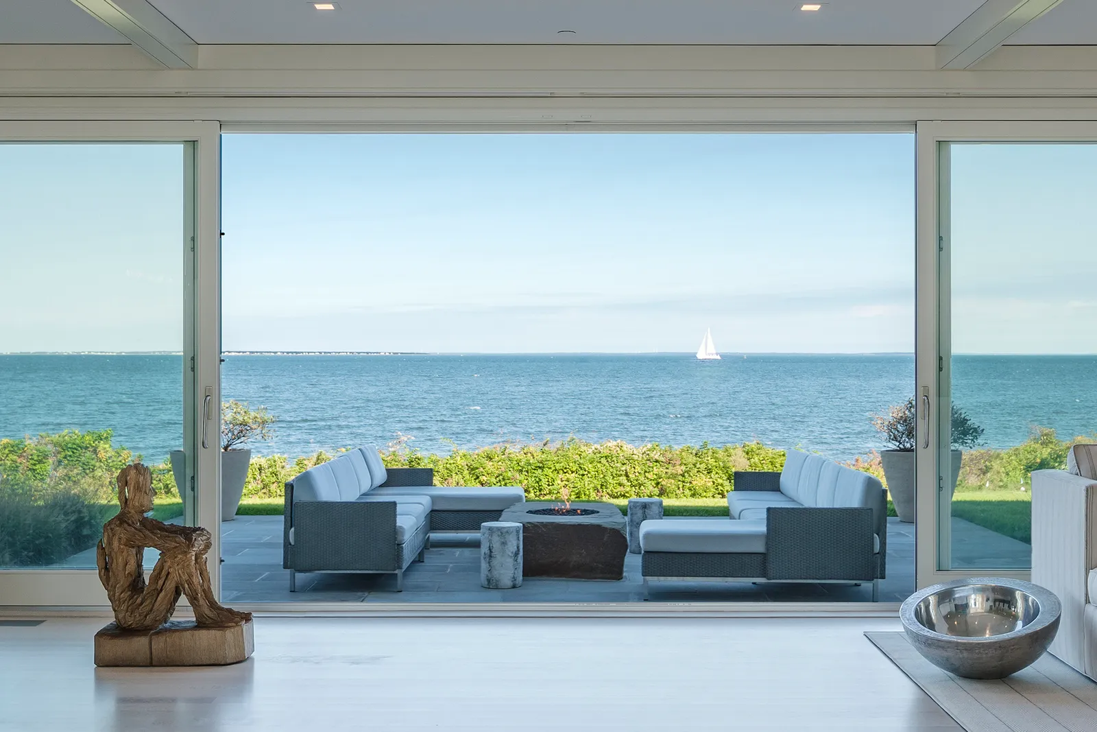 Waterfront living pavilion opening onto a bluestone fire-pit terrace