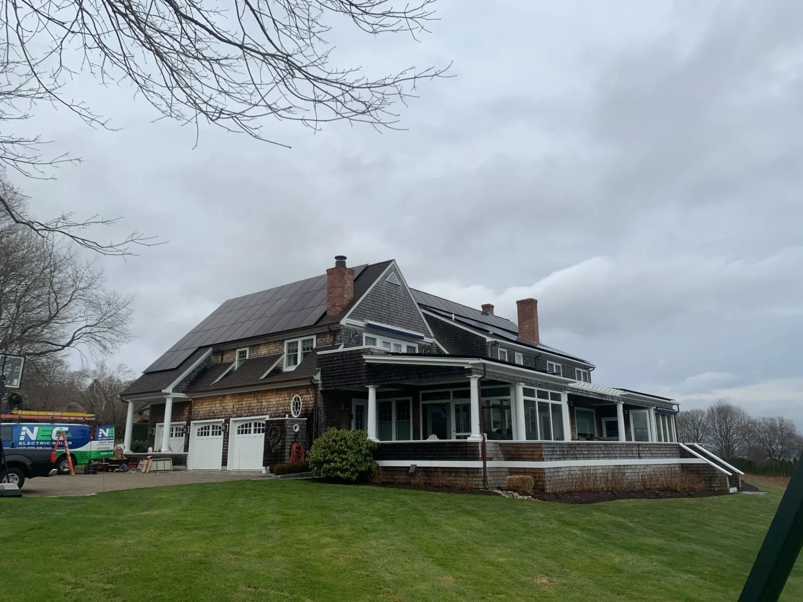 Shingle-style home with a full roof solar array, NEC van on site