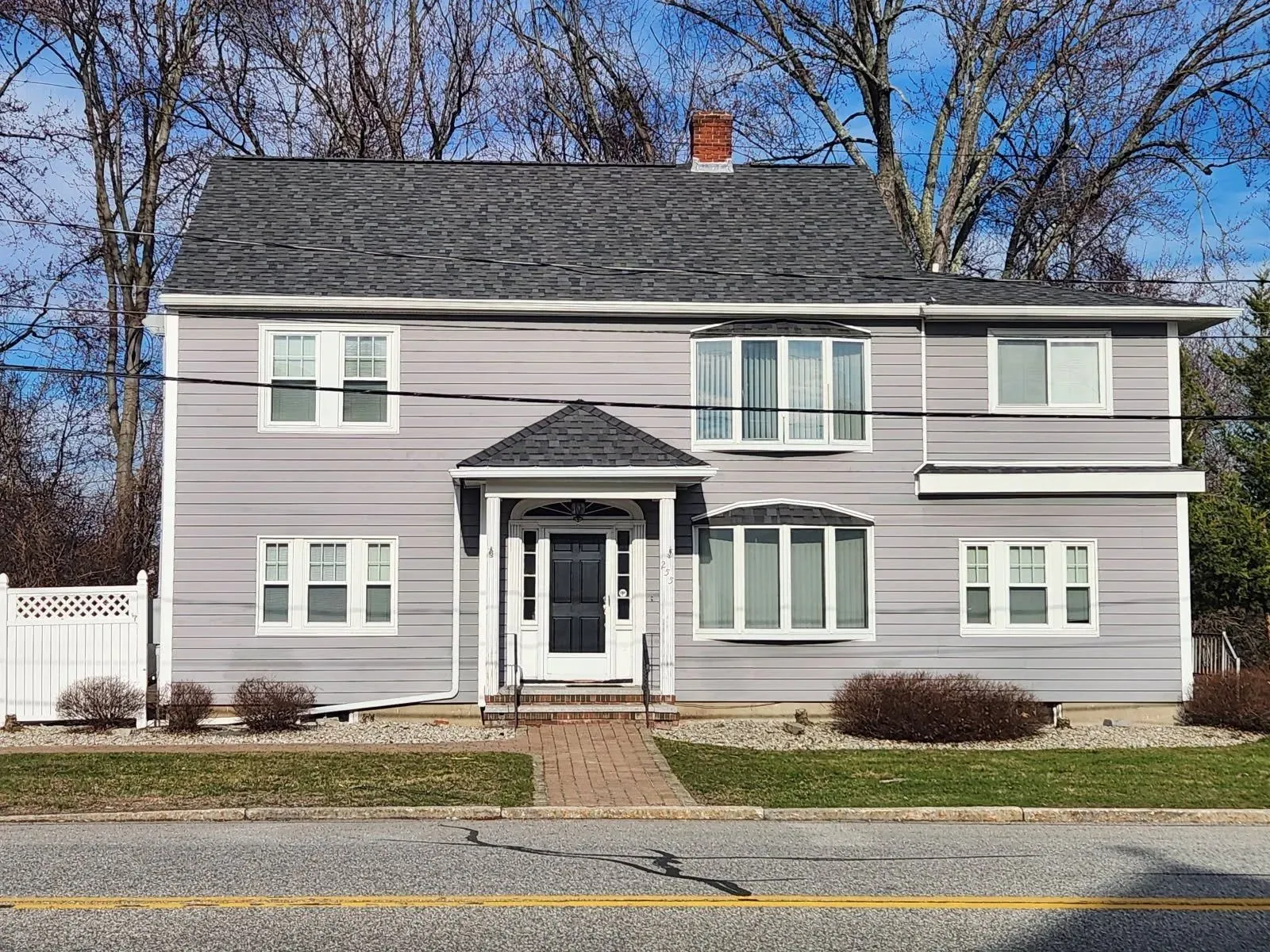 Two-story house with gray siding, white trim, and a brick pathway.