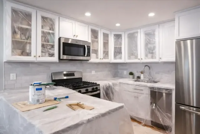Cabinet painting service showing protected kitchen cabinets and freshly painted finishes in a Waltham, MA home